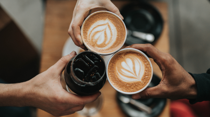 three hands each holding coffee cups and putting cups together to say cheers
